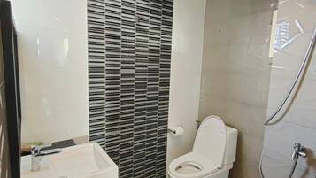 A modern bathroom with a toilet, sink, and shower.