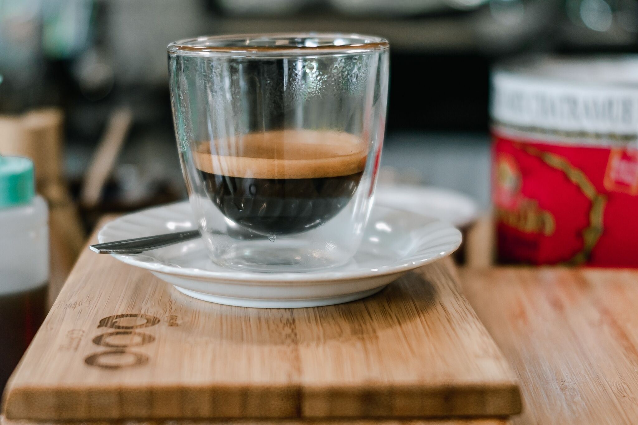 Una taza de café transparente sobre un platito blanco sobre una superficie de madera.