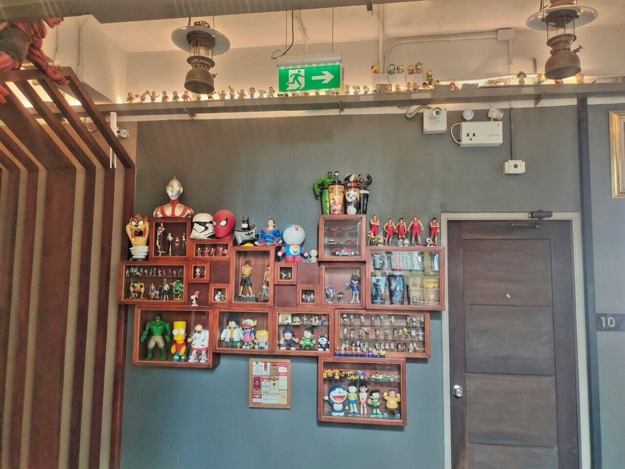A wall with various collectibles and memorabilia, including action figures and figurines, arranged in shelves and boxes.