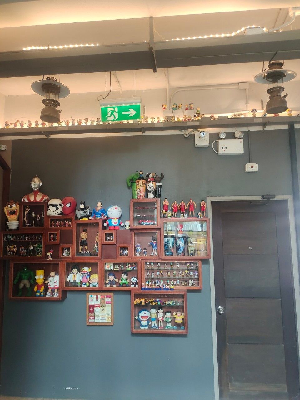 Una pared con varios objetos de colección y recuerdos, un cartel direccional verde y una puerta.
