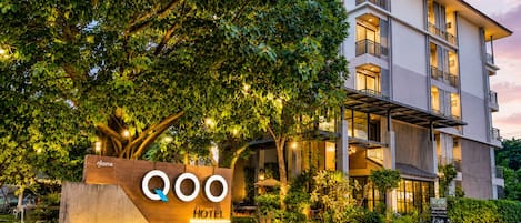 Un hotel con diseño moderno, un letrero y un jardín bien cuidado.