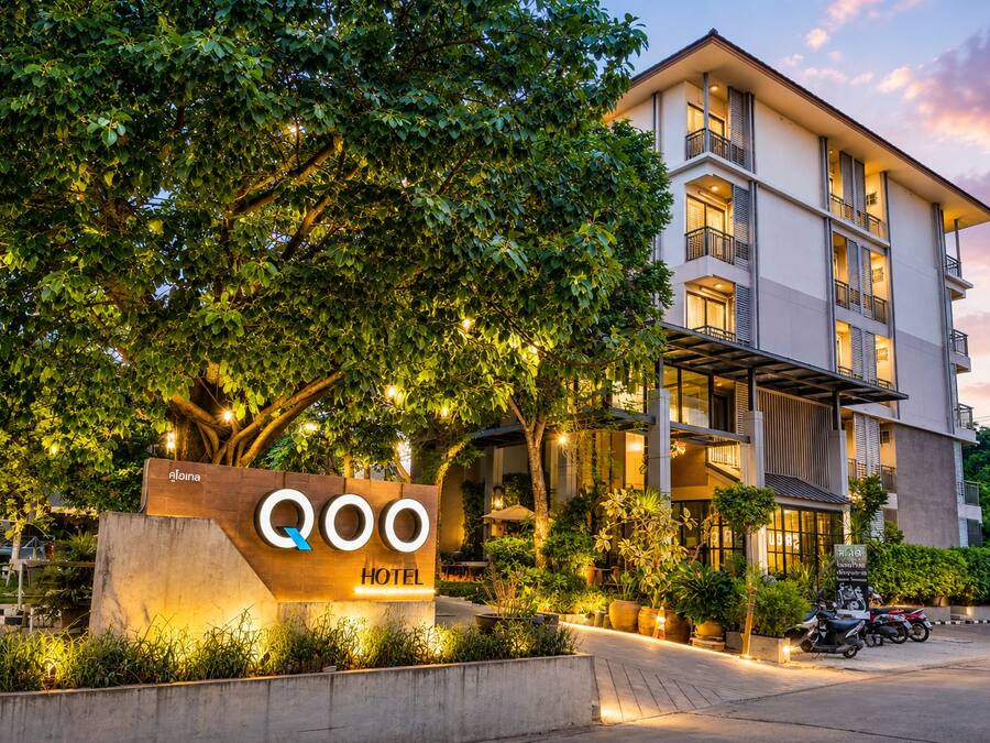 Um hotel com design moderno, uma placa de identificação e um jardim bem cuidado.