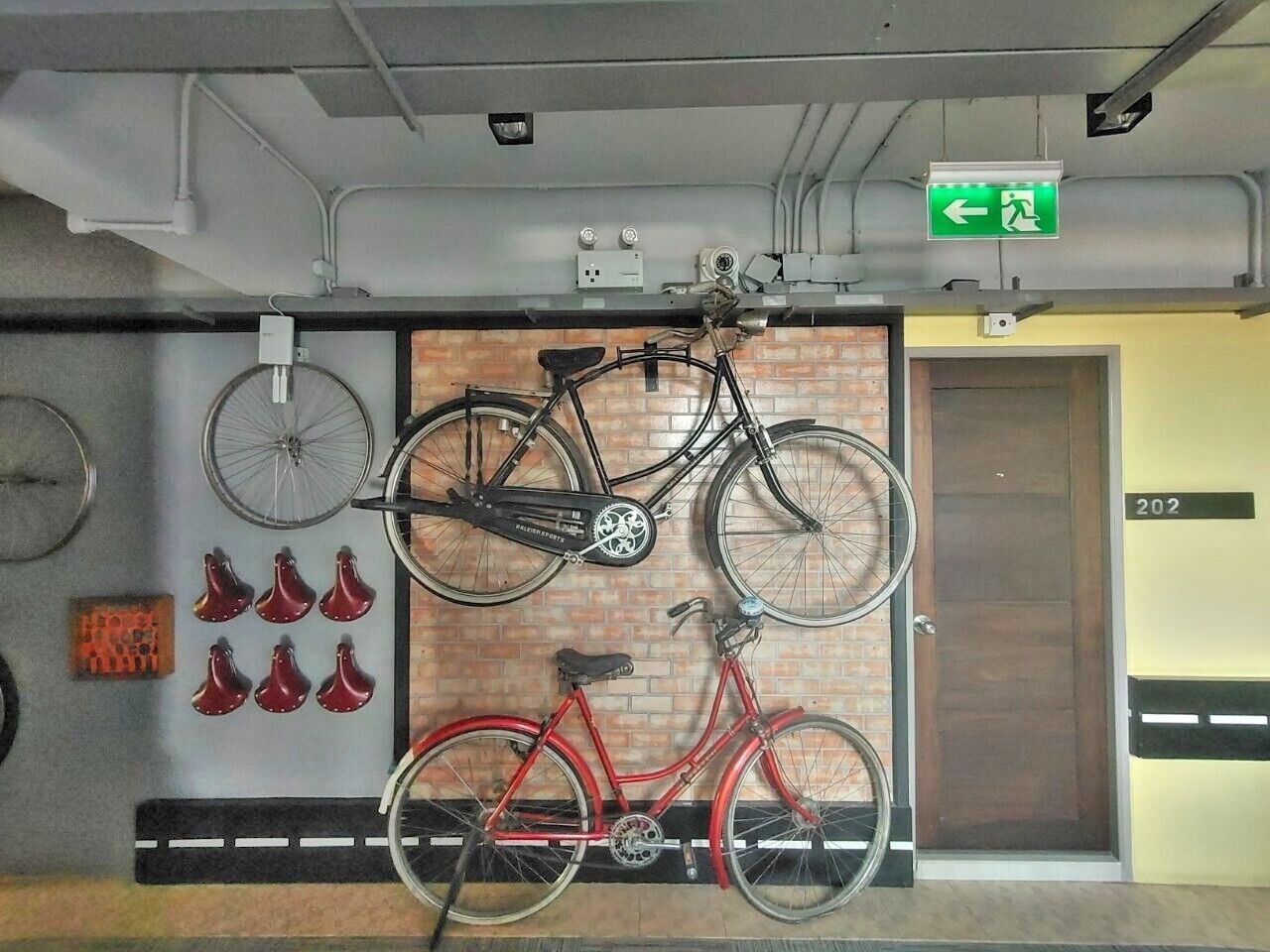 A parking garage with bicycles mounted on a wall and a door marked with the number 202.