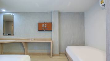 Habitación de hotel con cama, escritorio de madera, espejo y televisor de pared mostrando 'B2 Boutique & Budget'.