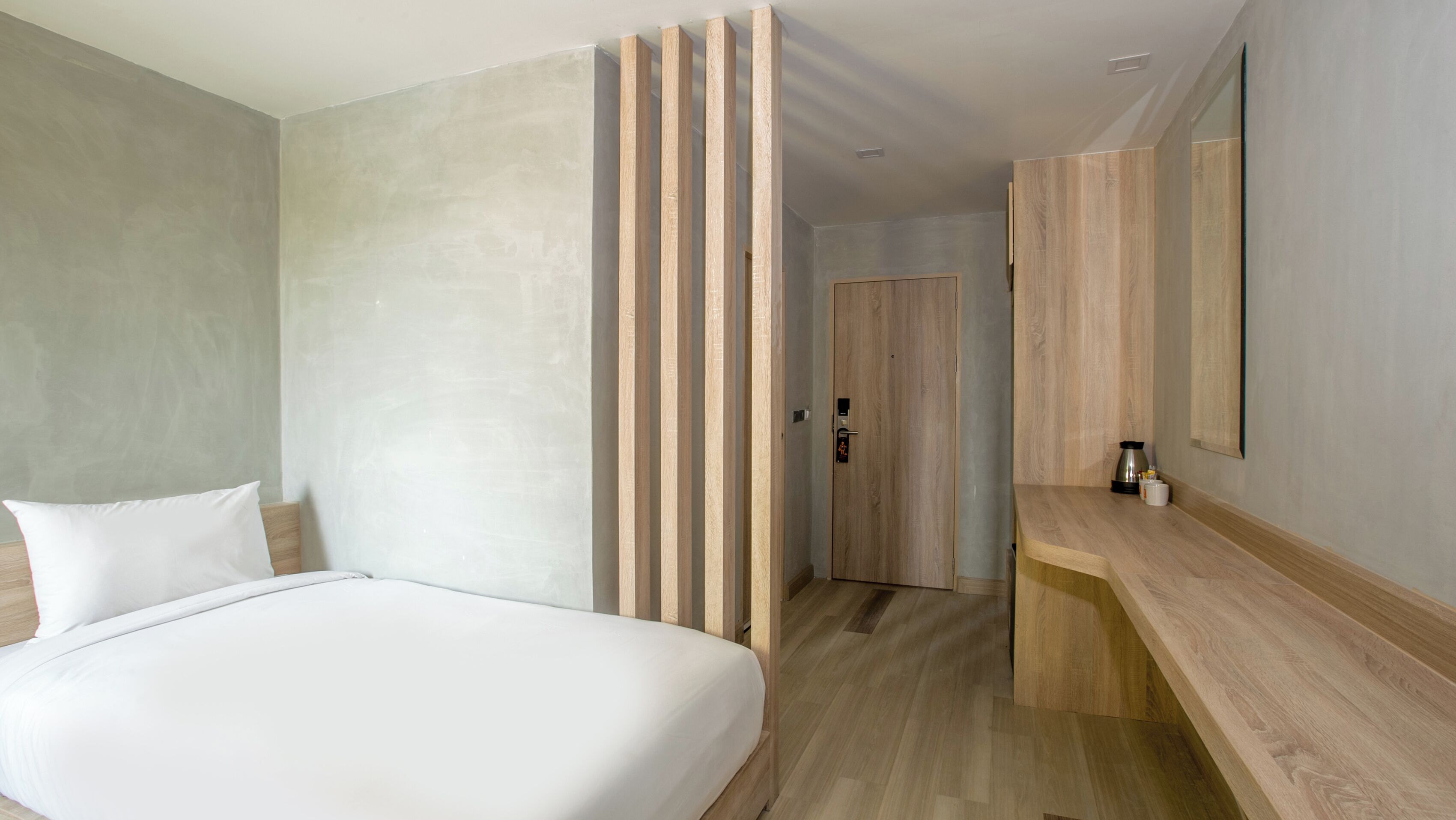 Et moderne hotelværelse med en stor seng, et træskrivebord og et spejl.
