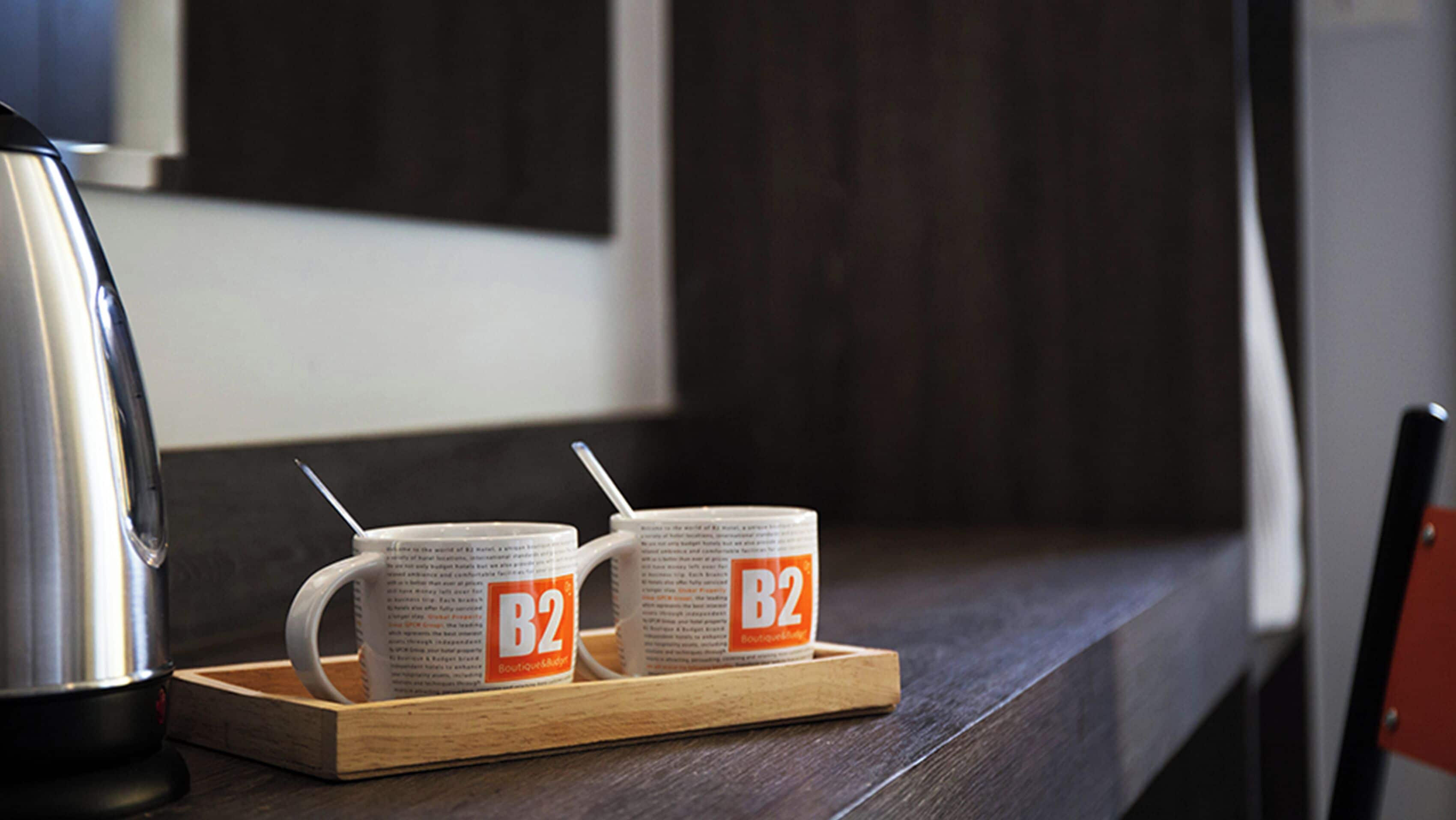 Dos tazas con el logo 'B2' sobre una bandeja de madera.