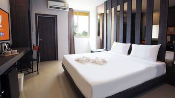 Una habitación de hotel moderna con una cama grande, un escritorio con silla, un televisor y un equipo de aire acondicionado.
