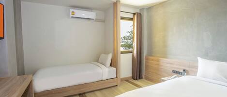 A hotel room with two beds, a wooden headboard, a window with curtains, and an air conditioning unit.