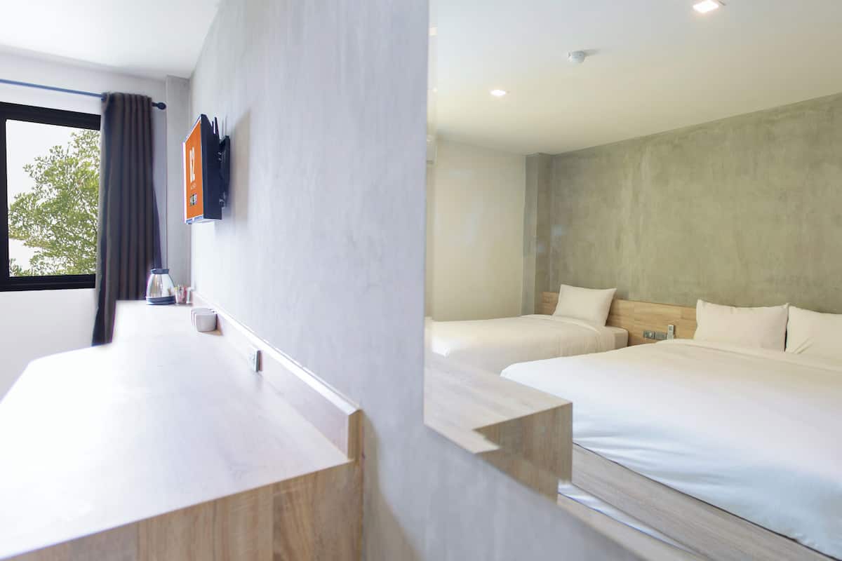 A modern hotel room with two beds, a wooden desk, and a large window with curtains.