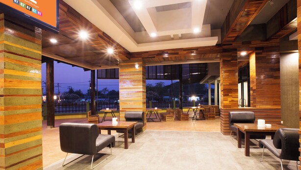 A modern interior with wooden paneling, a seating area with tables and chairs, and large windows offering a view of the outside. - B2 Buriram Boutique & Budget Hotel (Buriram)