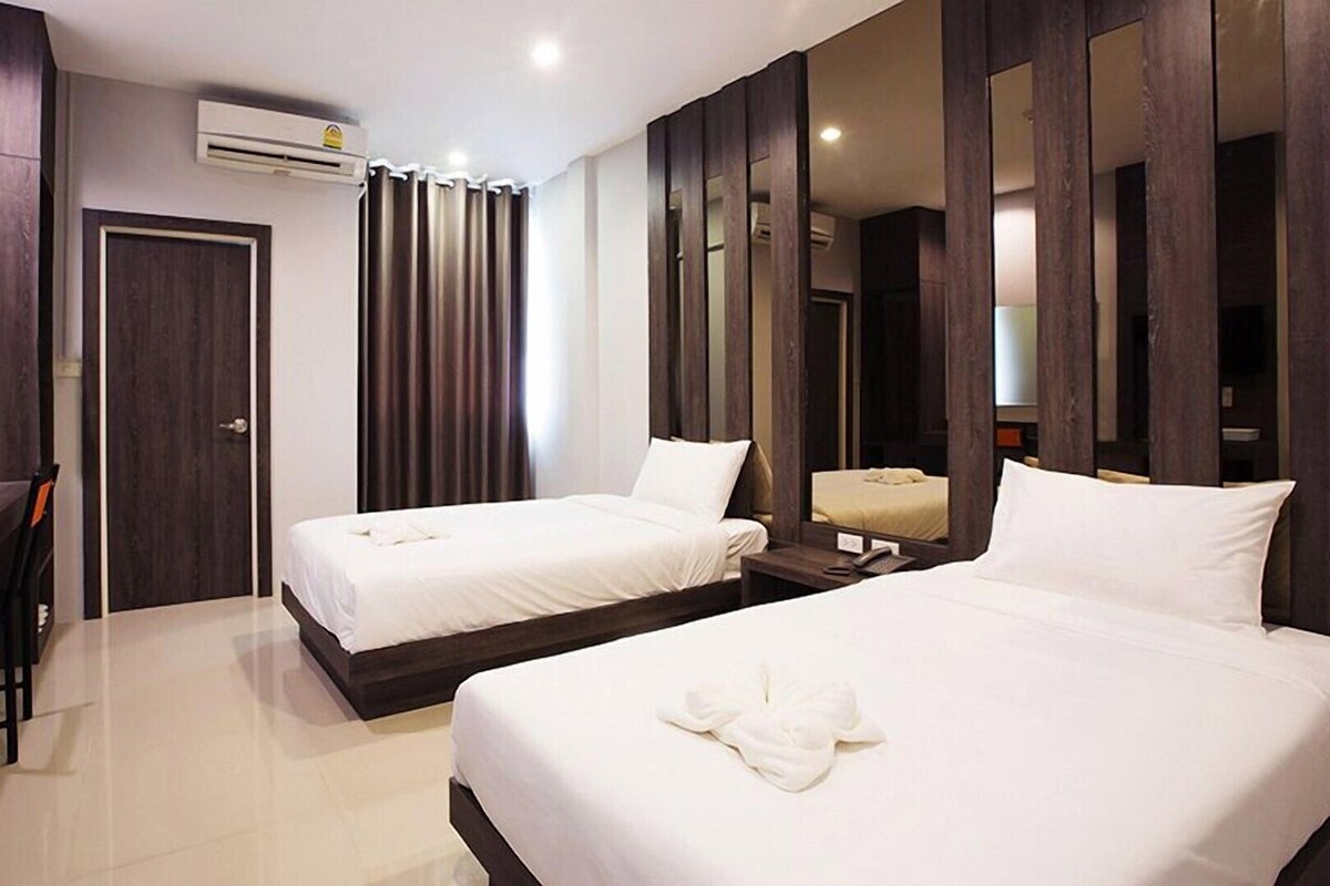 Habitación de hotel con dos camas, un escritorio, un espejo y un equipo de aire acondicionado.