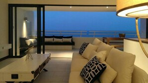 Un balcón con sofá, una mesa, una lámpara y vista al mar.