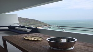 Una habitación moderna con una mesa de madera, un cuenco de metal y vista al océano.