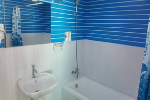 Un baño con lavamanos, bañera y paredes azul con rayas.