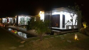 Un edificio moderno con piscina e iluminación exterior en la noche.