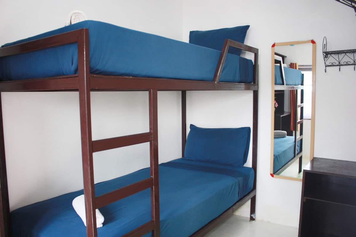 Un lit superposé avec une literie bleue et un miroir au mur.