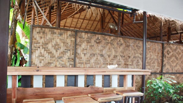 A wooden bench seating area with a woven wall backdrop. - Lantern Inn Koh Lipe (Koh Lipe)