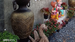 Une enseigne pour la maison d’hôtes Yotin, avec un grand vase décoratif et des plantes en pot.