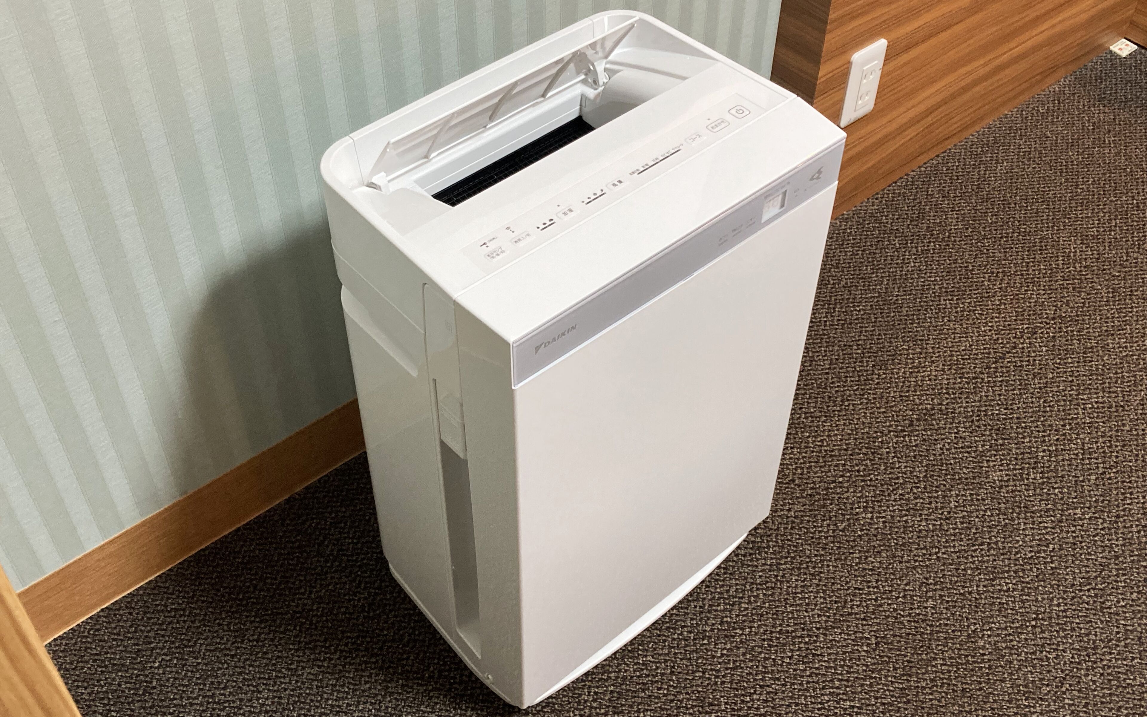 A white, modern, compact, wall-mounted, single-serve coffee machine with a control panel and a water reservoir.