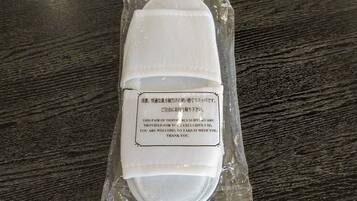 A pair of disposable slippers in a plastic package with a label.