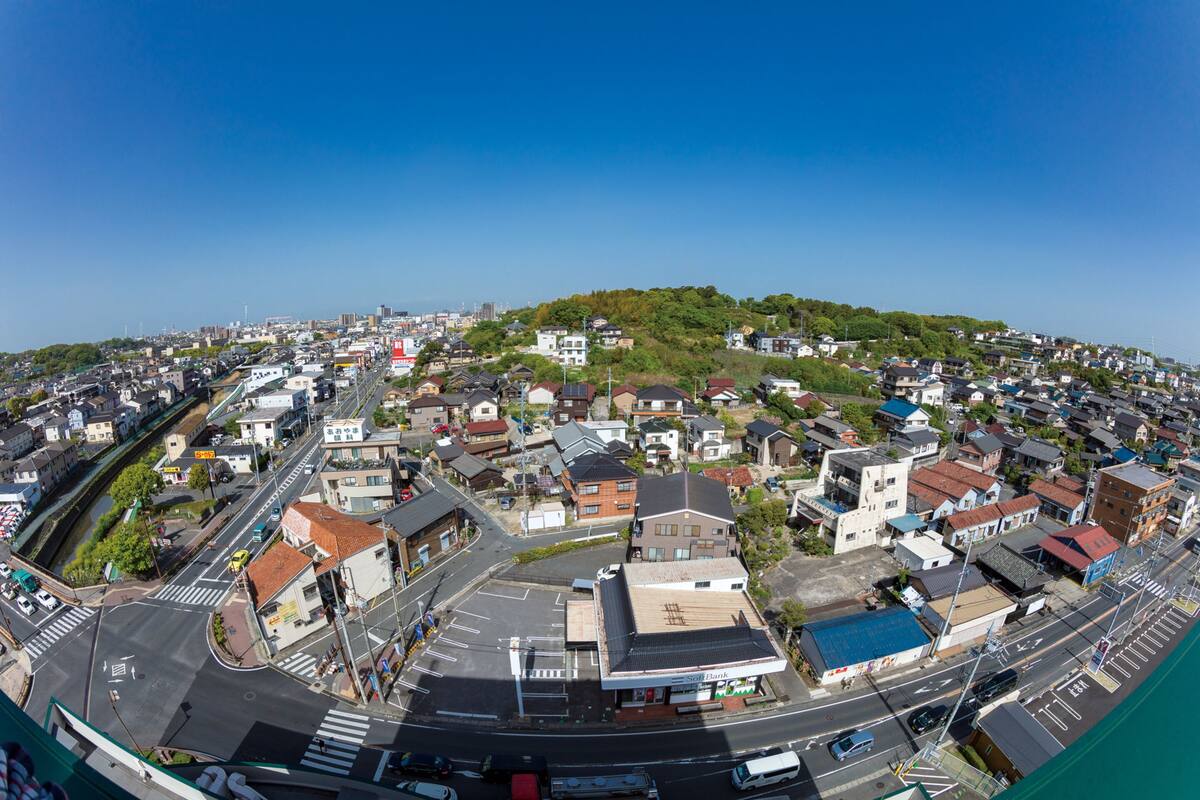 Une vue panoramique d’un quartier résidentiel avec des maisons, des routes et une colline verdoyante.