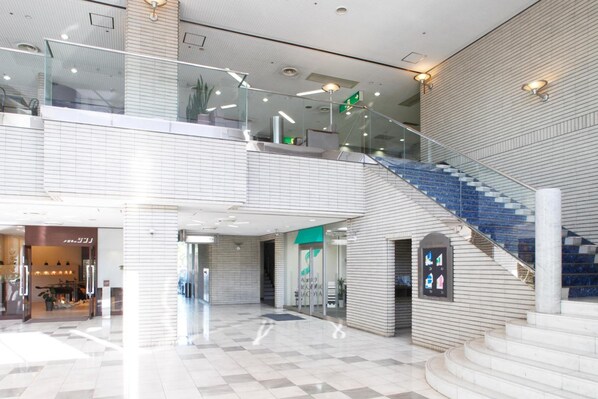 A spacious indoor area with a staircase, glass railings, and a tiled floor. - Tokai City Hotel (Tokai)