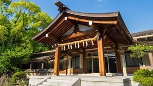 Een traditioneel Japans gebouw met een gebogen dak, houten pilaren en een stenen trap naar de ingang.