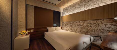 Un dormitorio con una cama grande, cabecera de madera, mesita de noche con un florero y pared con estampado floral.