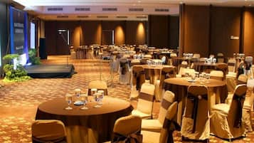 Un salón de conferencias con mesas redondas, sillas y un escenario.