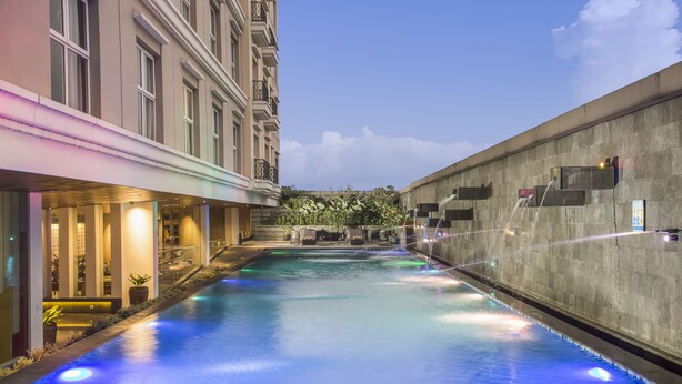 A swimming pool with a view of a building and a concrete wall. - Swiss-belhotel Bogor (Bogor)