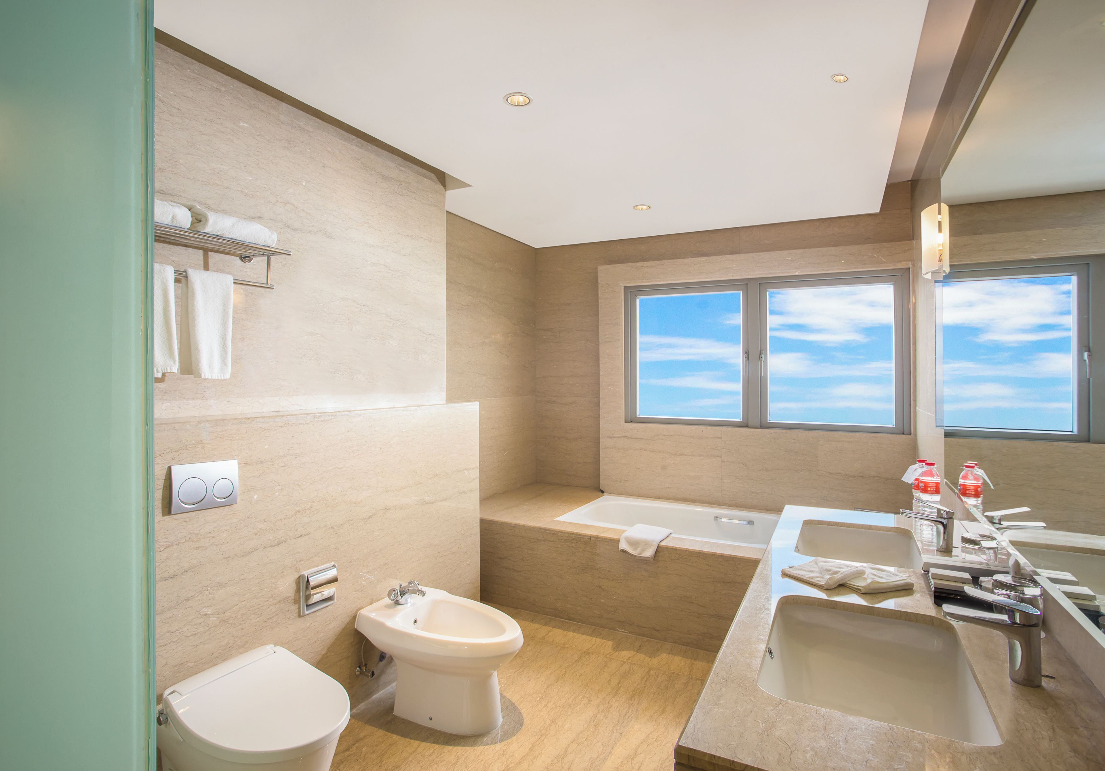 A modern bathroom with a bidet, toilet, and a bathtub.