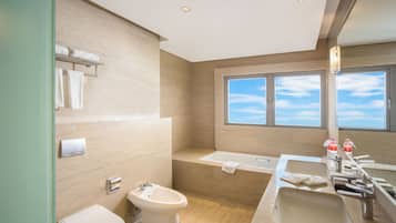 A modern bathroom with a bidet, toilet, and a bathtub.