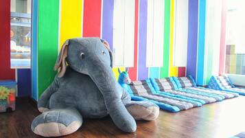 A room with a colorful striped wall, a plush elephant toy, and a blue and gray striped rug.