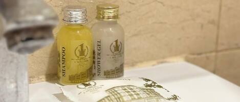 A bathroom with a white sink, two bottles of shampoo and shower gel, and a towel with a building design.