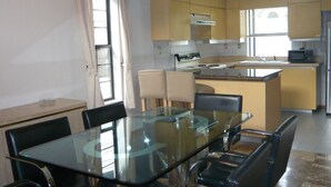 Une cuisine moderne avec une table et des chaises en verre, une cuisinière encastrée et un four à micro-ondes.