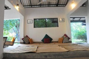 A room with a low ceiling, a window with a metal screen, and a bench with cushions. - Water's Edge Anuradhapura (Anuradhapura)