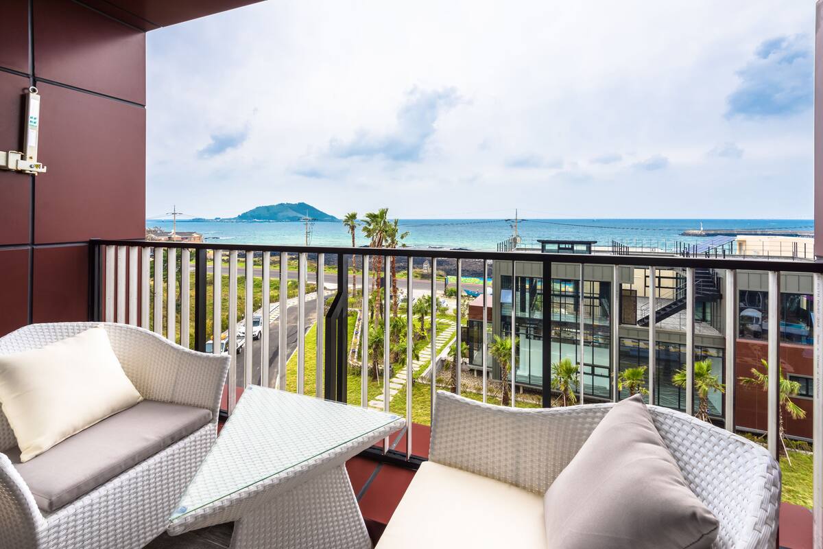 A balcony with wicker furniture and a view of the ocean.