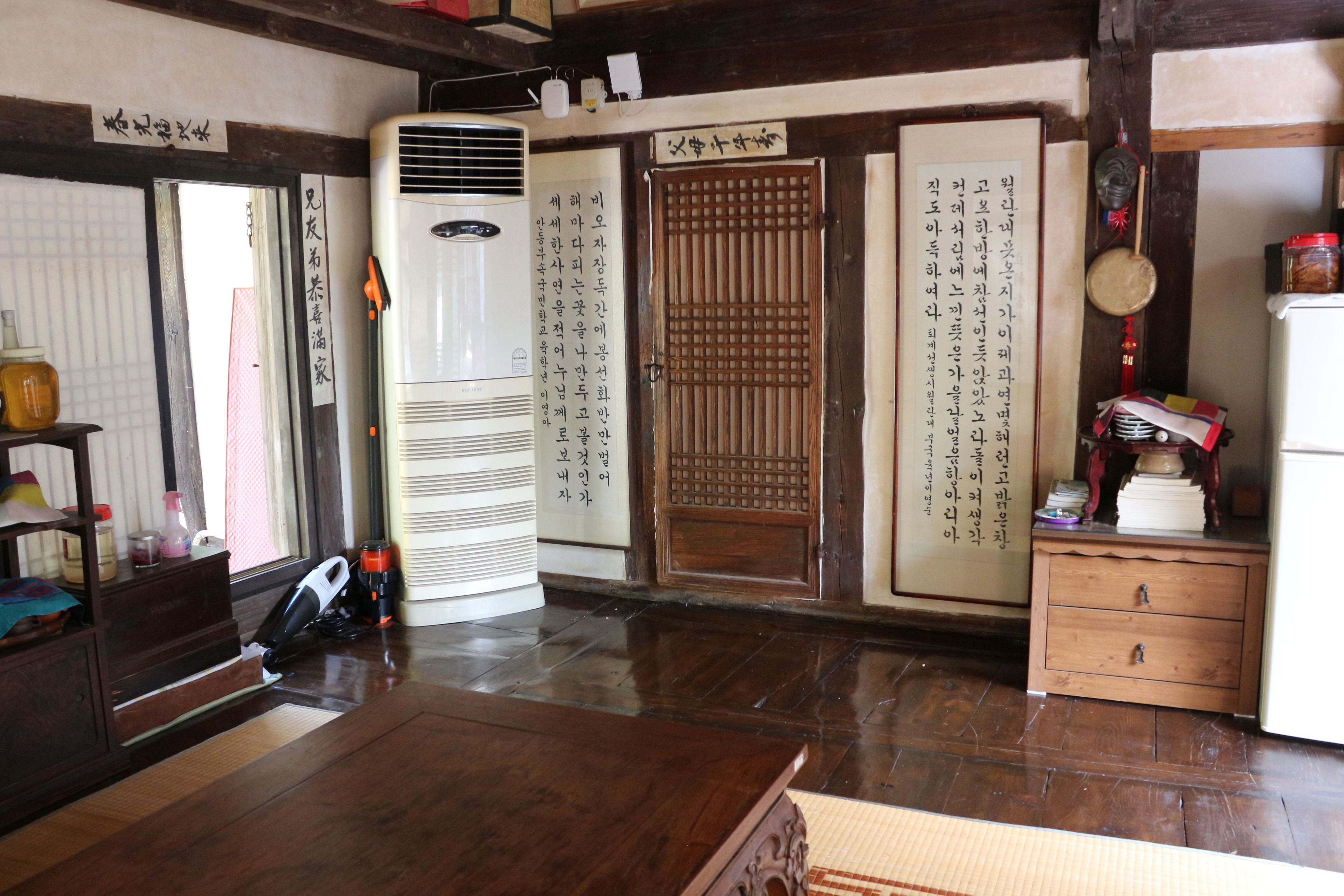 Una habitación japonesa tradicional con suelo de tatami, una mesa de madera, un calentador y un puertas correderas con caligrafía.
