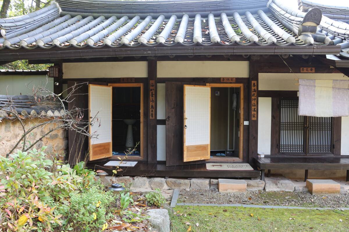 A traditional Japanese building with a tiled roof, wooden doors, and a stone pathway leading to the entrance.