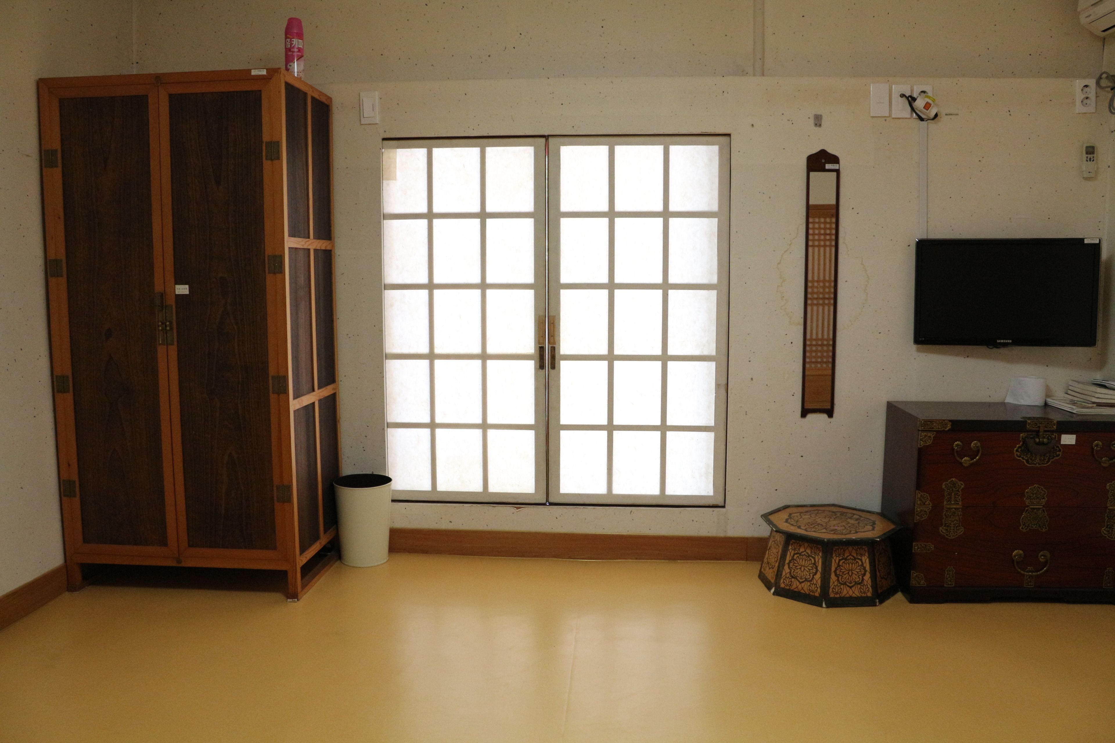 A room with a sliding door, a television, a cabinet, and a small stool.