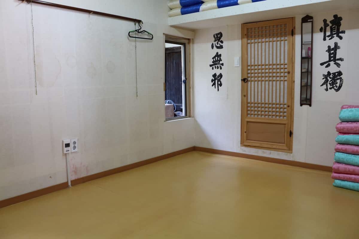 A room with a wooden floor, a sliding door, and a wall with Japanese characters.