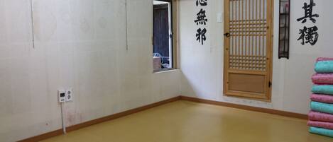 Una habitación con piso de madera, una puerta corredera y una pared con caracteres japoneses.