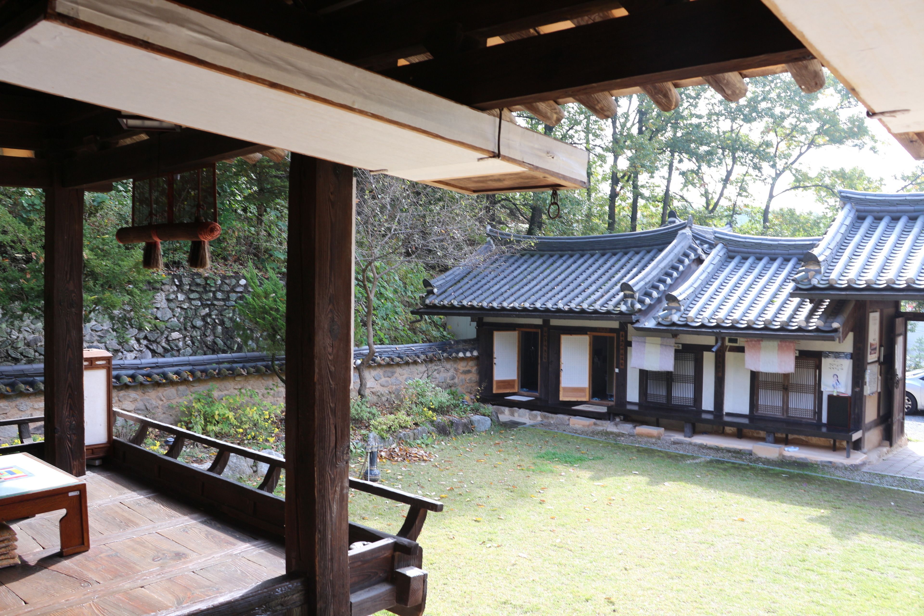 Ein traditionelles japanisches Gebäude mit einem Ziegeldach, Holzkonstruktion, einer Steinmauer und einem begrünten Innenhof.