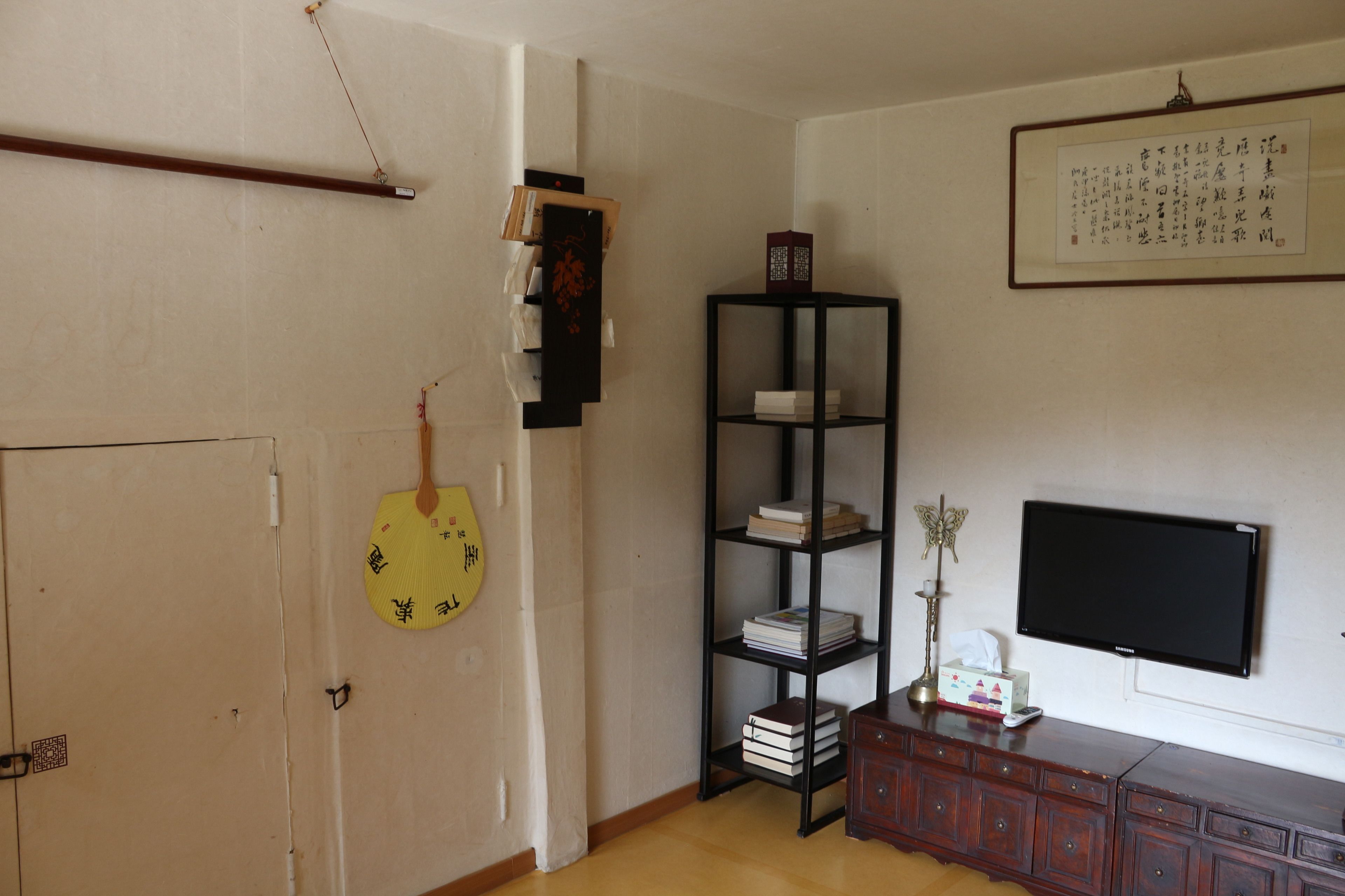 A room with a wooden cabinet, a black TV stand, a bookshelf, and a door.