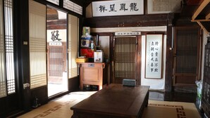 A traditional Japanese room with tatami flooring, a wooden table, sliding doors, and a sign with Japanese characters. - Chiam Gotaek (Andong)