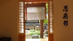 A traditional Japanese room with tatami flooring, a shoji screen door, and a calligraphy scroll on the wall. - Chiam Gotaek (Andong)