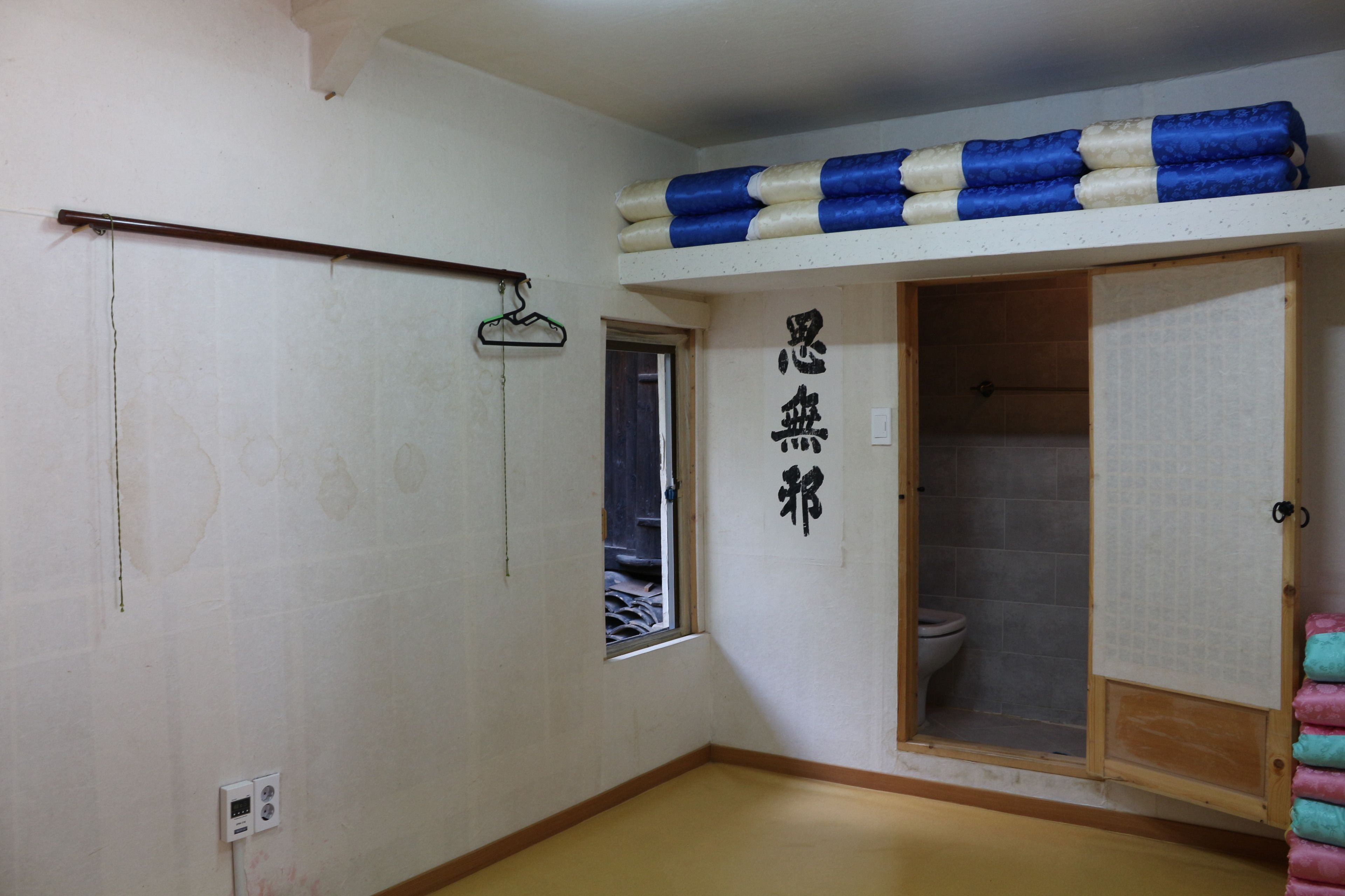 A room with a bunk bed, a toilet, and a small window.