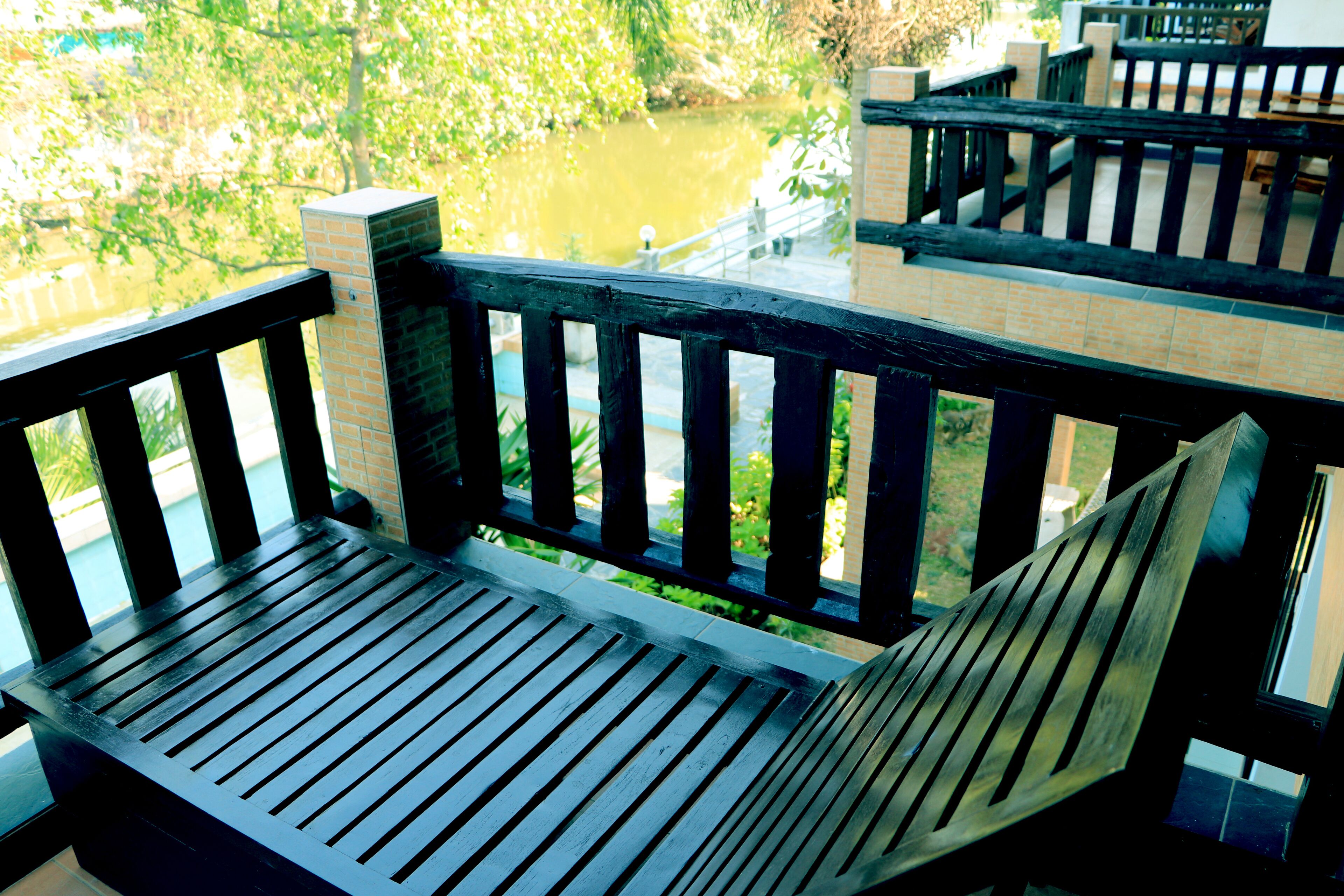 Een houten bank met een metalen leuning, met uitzicht op water en groen.