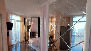 A spacious hotel room with a large bed, a television, and a glass partition. - Rock Hotel First Line (Batumi)