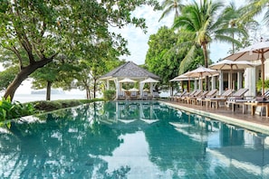 A pool with lounge chairs and umbrellas, surrounded by trees and a gazebo. - Cape Kudu Hotel (Ko Yao)